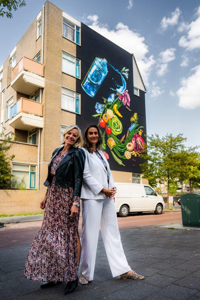 Martine Gosselink (rechts) en Kristel van der Linden voor de mural van kunstenares Nadia van Luijk op de hoek van de Smitstraat en het Joubertplantsoen/